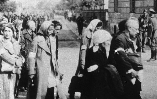 Jews walk in a long column through the streets of Rzeszow during a deportation action from the ghetto. July 1942